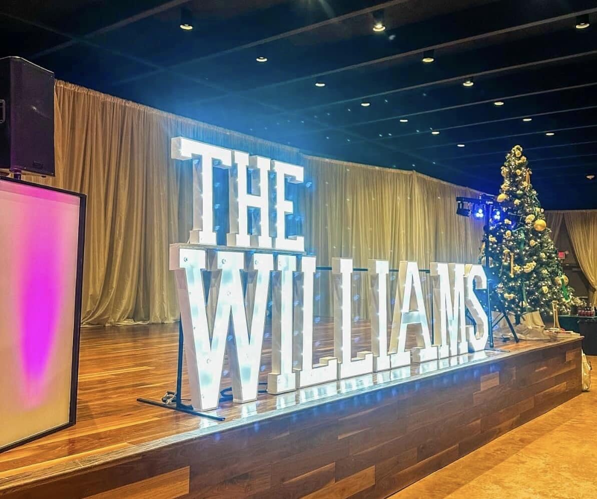 Marquee letters spelling THE WILLIAMS lit across a reception stage
