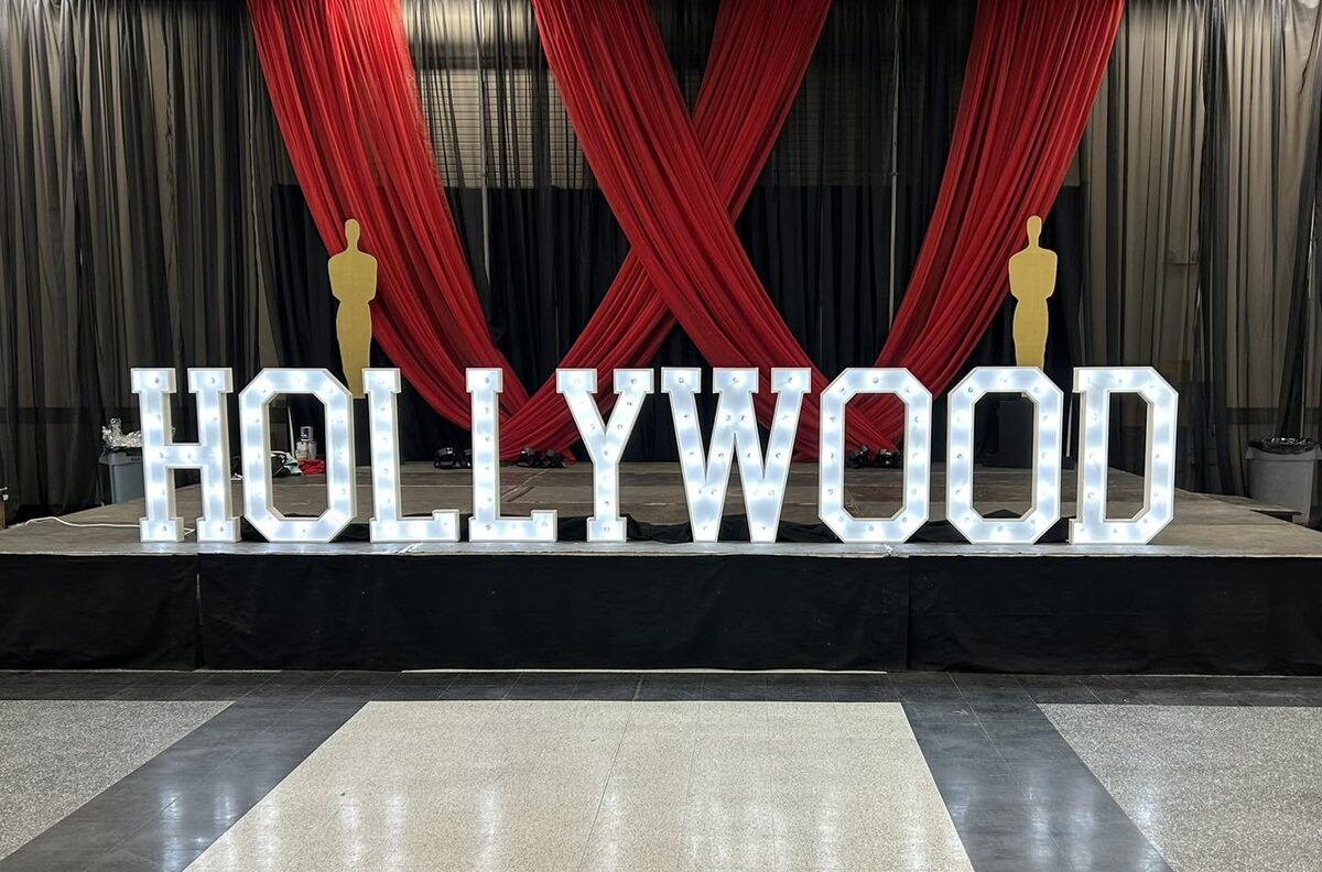 Lit marquee letters spelling HOLLYWOOD in front of red stage curtains