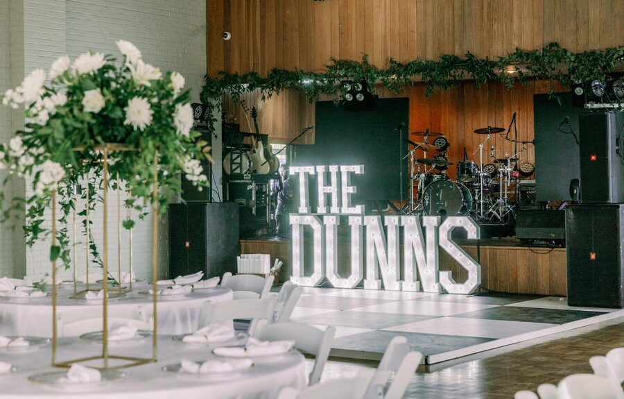 THE DUNNS in lit letters beside a white dance floor and floral arrangements