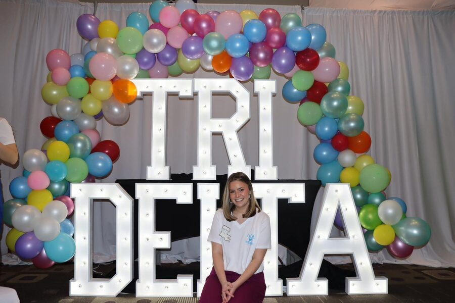 TRI DELTA in lit letters under a rainbow balloon arch